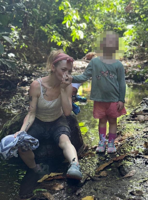 Hannah Spearritt sat on a rock by a stream with her kids beside her in a woodland.