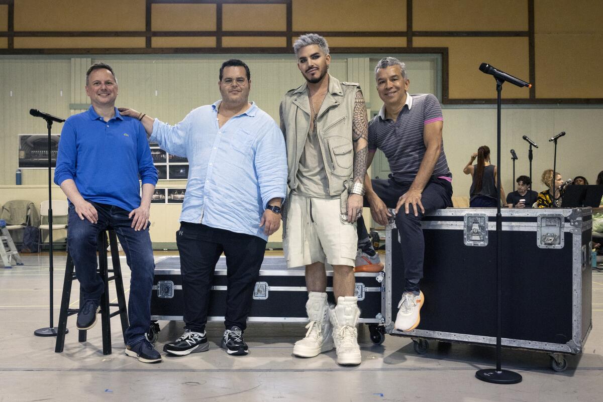 Brian Grohl, Josh Gad, Adam Lambert and Sergio Trujillo stand in a rehearsal room in front of black road boxes.