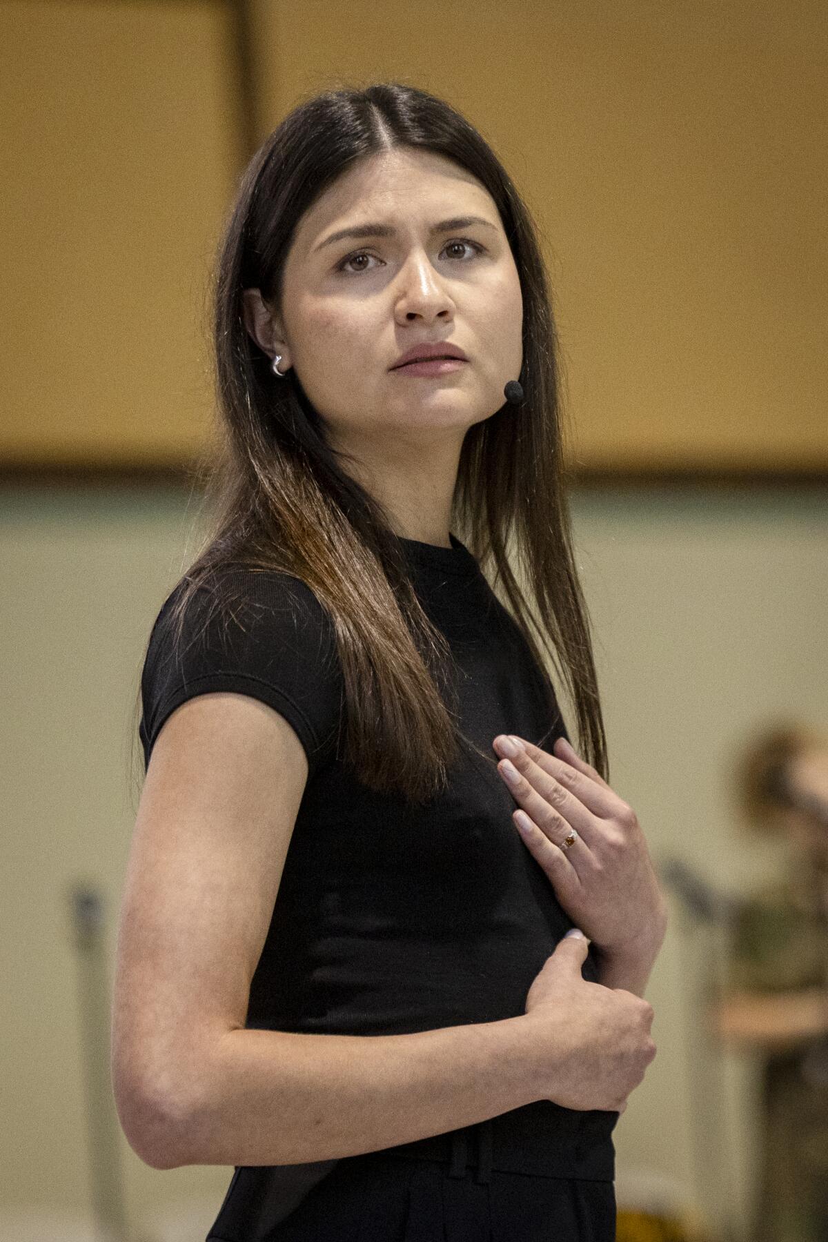 Phillipa Soo, in black T-shit, puts her hand on her chest. 