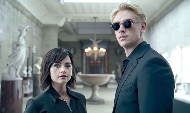 A woman stands next to a man in black glasses