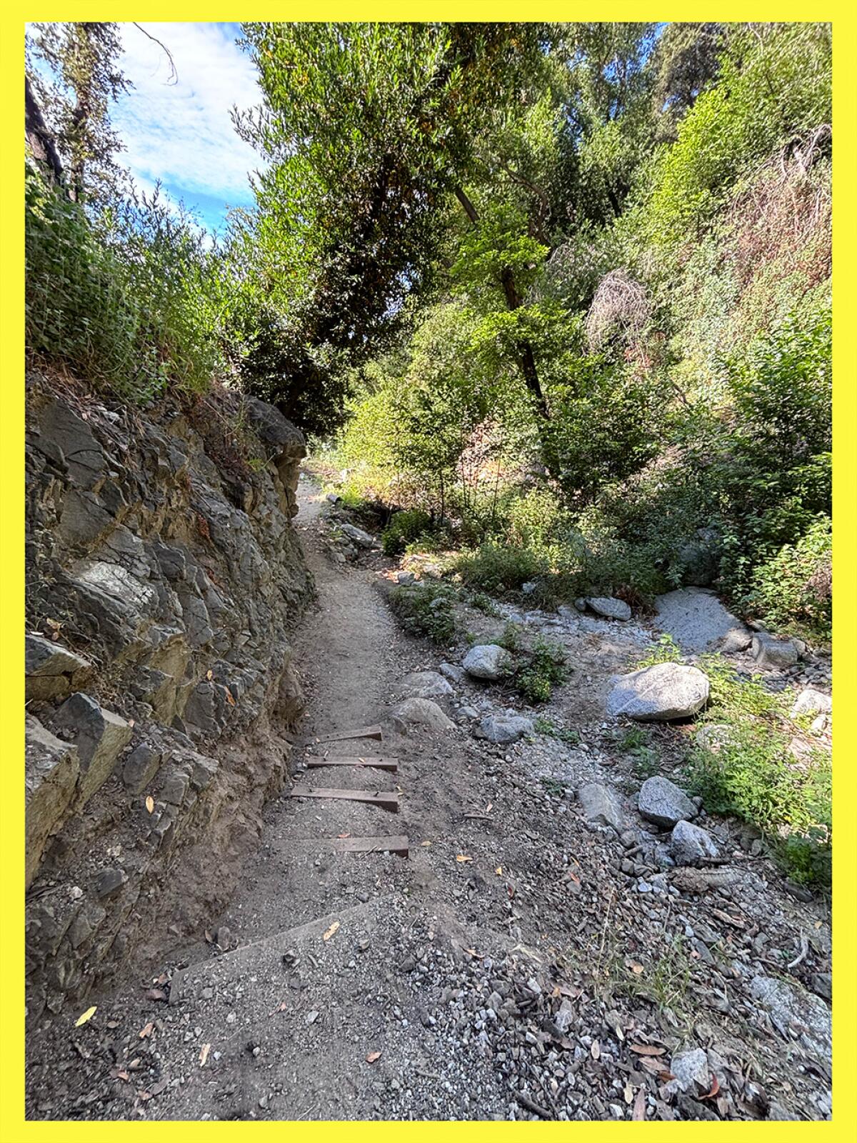Greenery shaded trail around rocks.