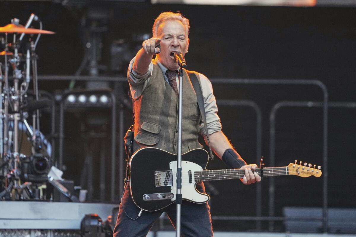 Bruce Springsteen on stage in Berlin holding a guitar and yelling into a microphone