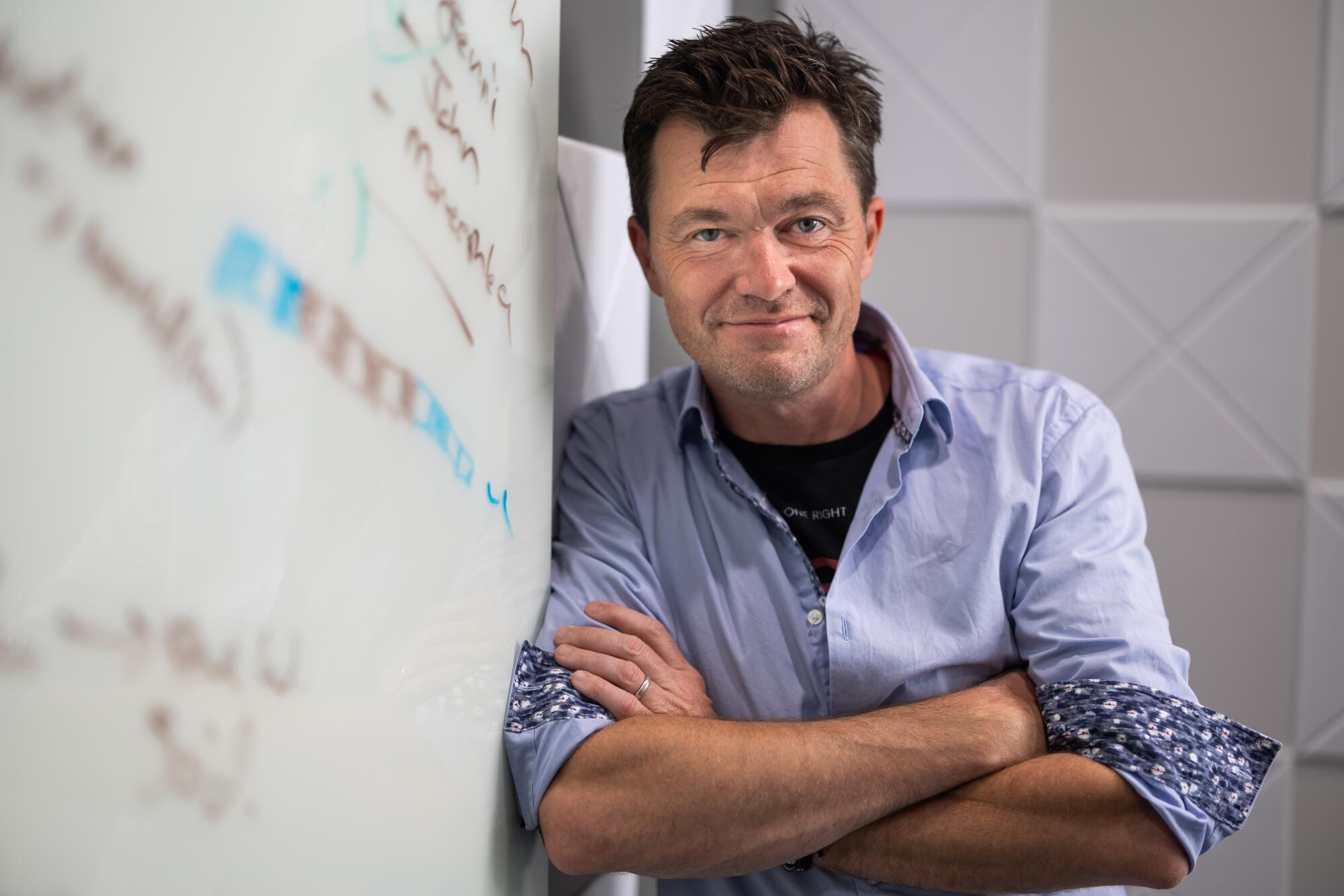 A man crosses his arms and smiles in an office.