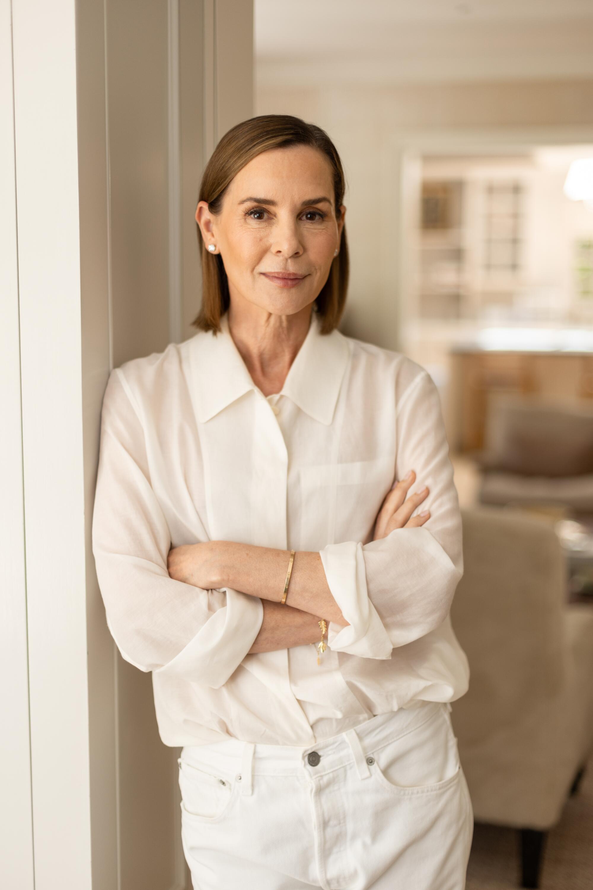 A woman crosses her arms in a light, airy living room.