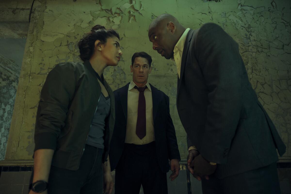 A woman and a man look into each others eyes as another man stands in the background between them.