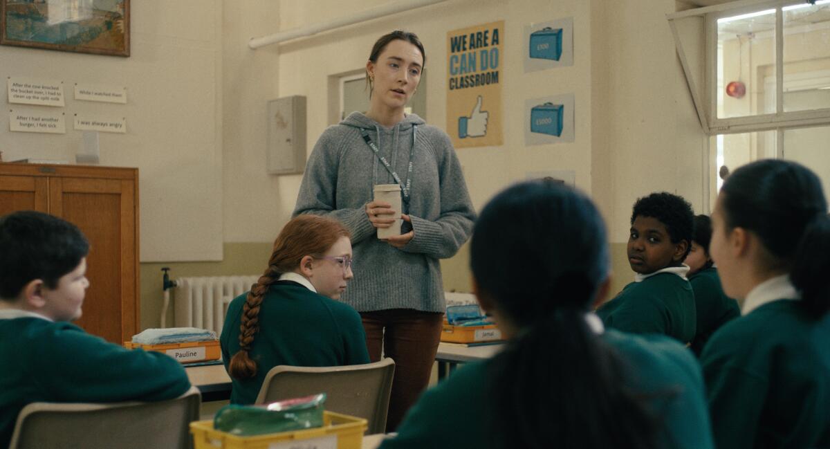 A woman in a gray hoodie speaking to a classroom of students