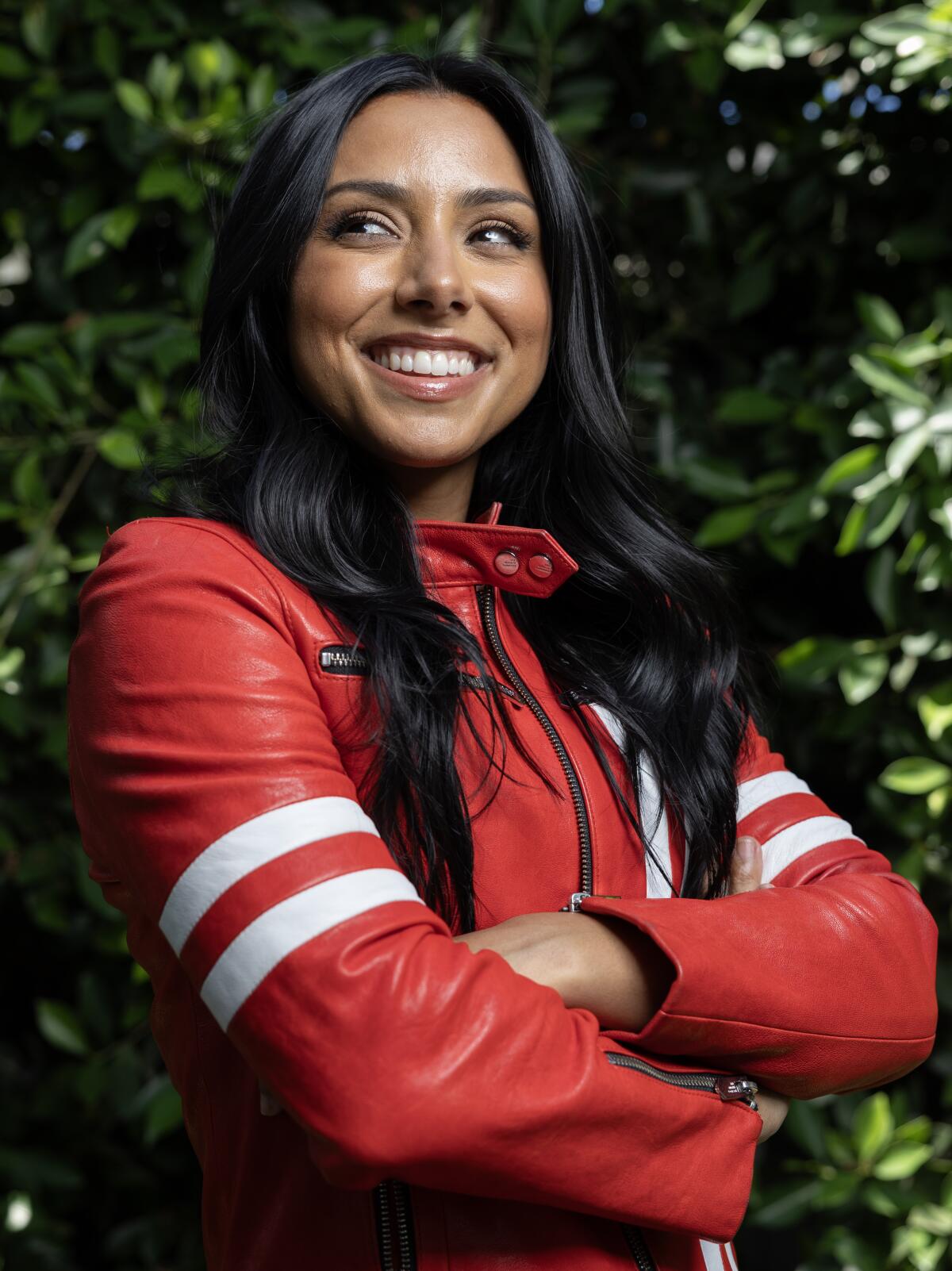  A photo of a woman smiling and crossing her arms, wearing a red jacket