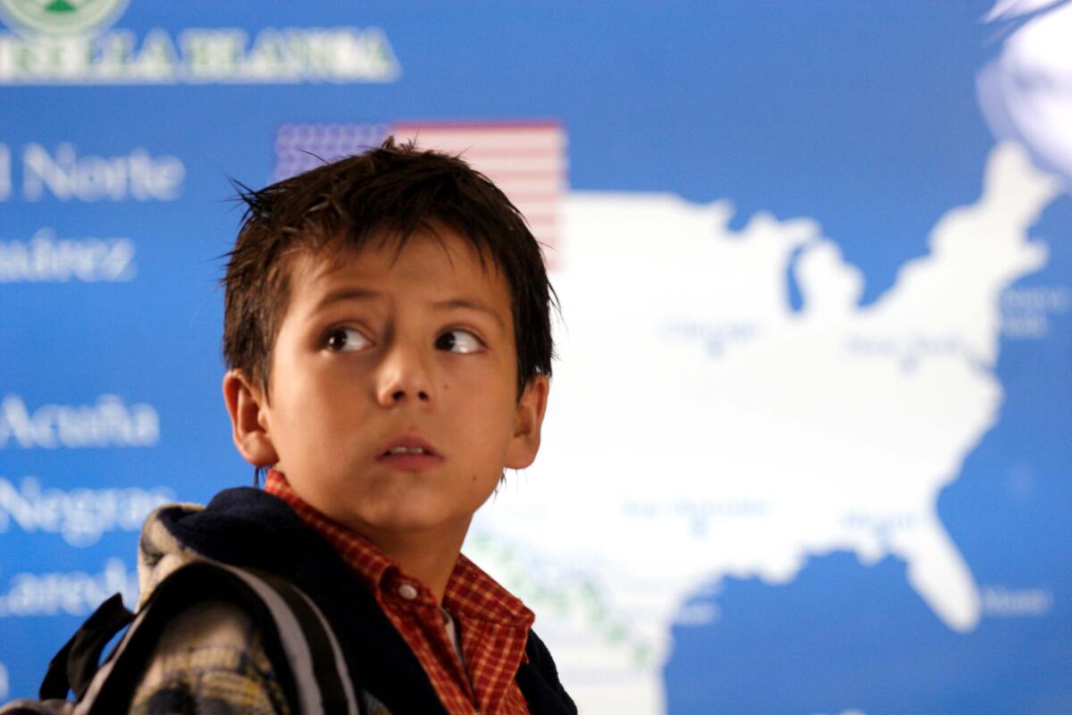 A young boy stands in front of a map of the U.S.