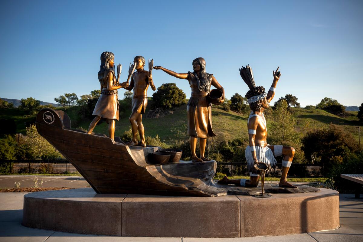 A large bronze sculpture depicting two Chumash children dancing, a gesturing woman and a kneeling man pointing to the sky.