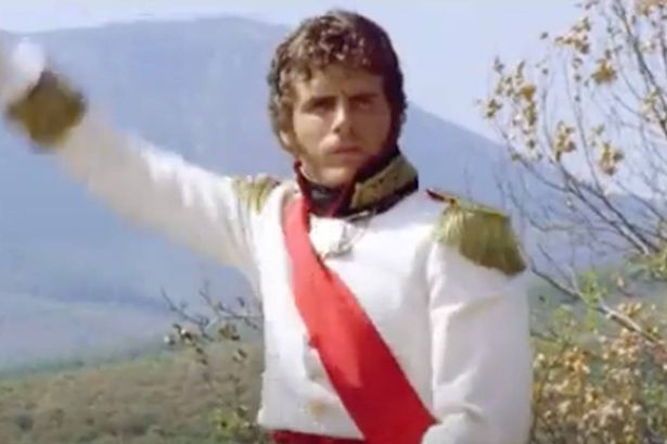 A soldier in white with a red sash looks serious