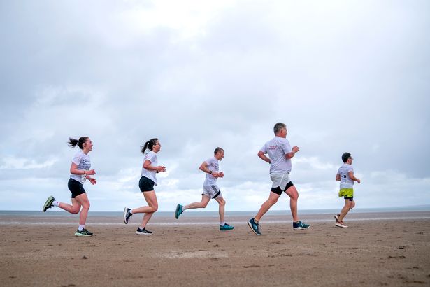 Runners, wearing white, compete in the annual Chariots of Fire race along the West Sands Beach in St Andrews, Fife