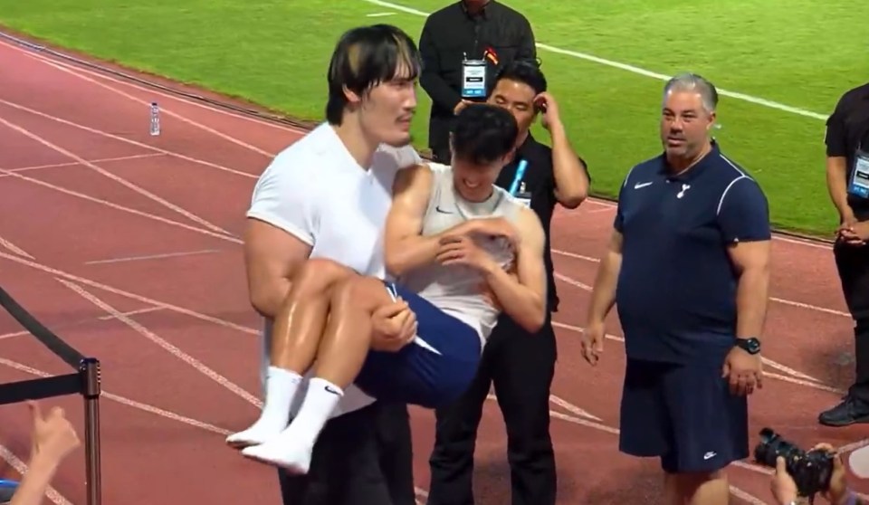 A man carrying another man on a running track.