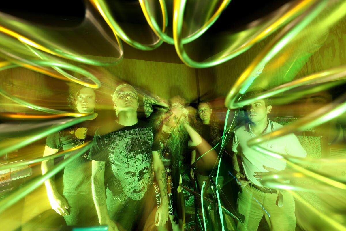 Band posing in practice space against a psychedelic background