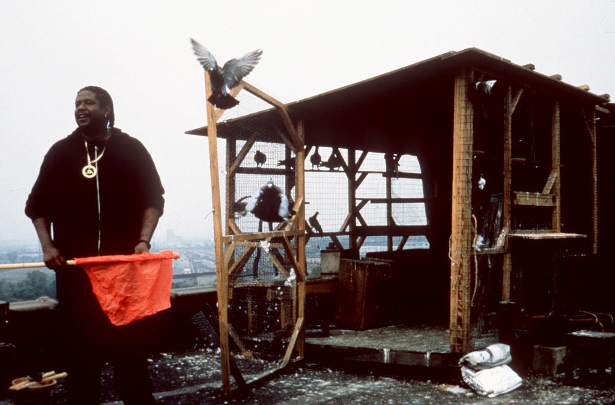 A man in black holding an orange flag in front of a shed-like structure