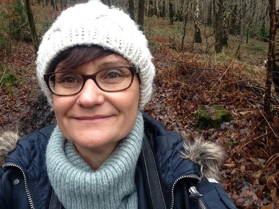 Self-portrait of a woman in a wooded area.
