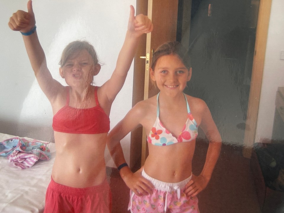 Two young girls in swimsuits giving thumbs up.