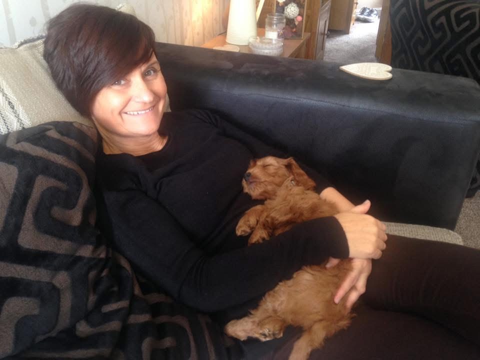 Woman cuddling a sleeping puppy.