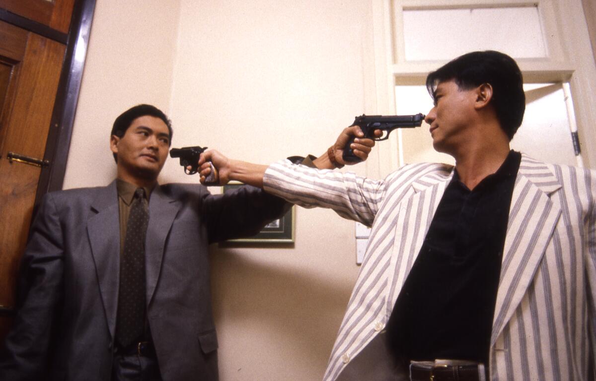 Two men point pistols at each other.