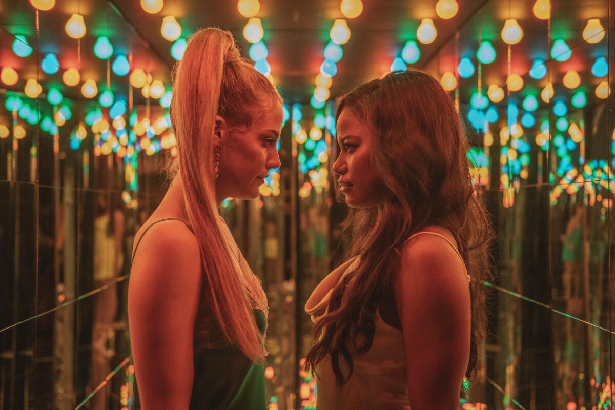 Two women with big hair have a showdown in a hallway.