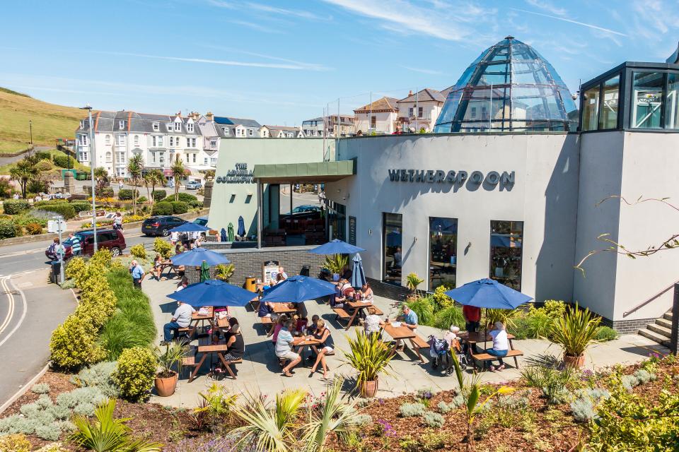 The Admiral Collingwood Wetherspoon pub in Ilfracombe, Devon, with patrons seated at outdoor tables.