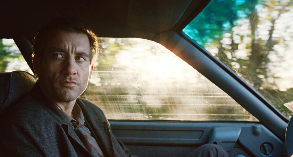A nervous man sits in the front of a car.