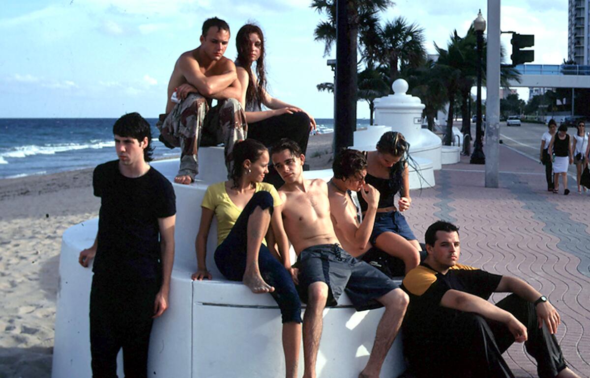 Several young people lounge on a beach.