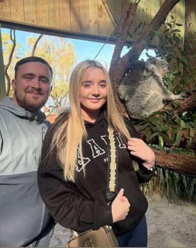 Couple posing with a koala at a zoo.