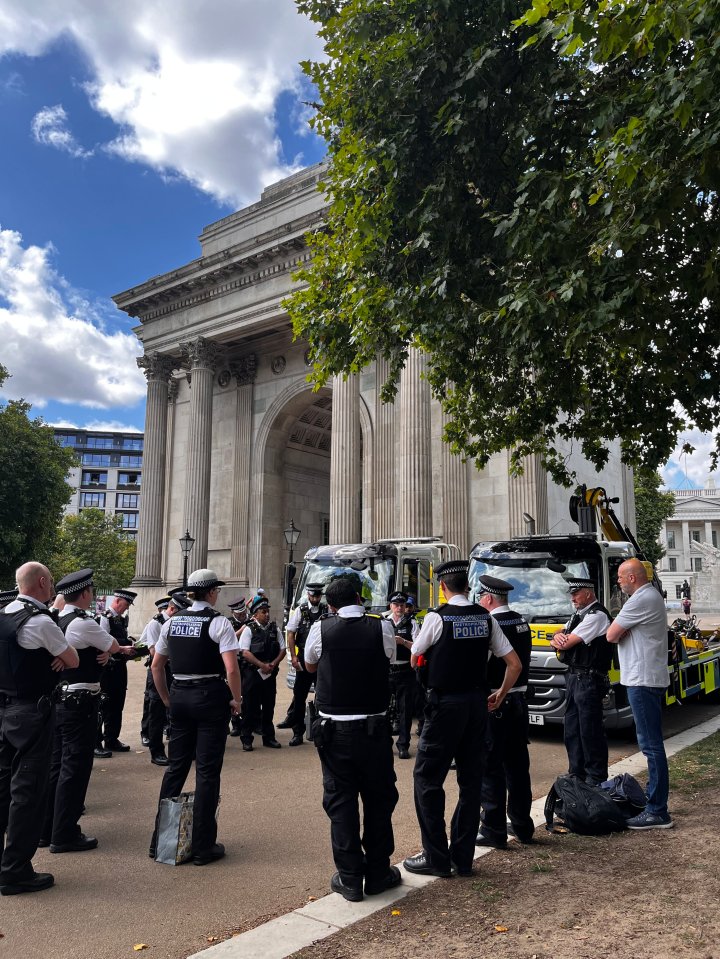 Police officers standing near a tow truck in front of an archway.