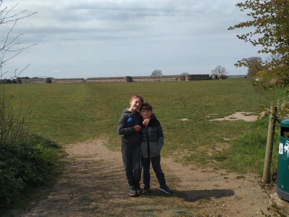 Two boys standing in front of a stone wall at a National Trust site.