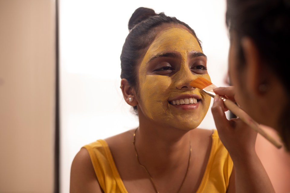 Woman applying a yellow face mask.