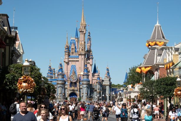 (FILES) Visitors walk along Main Street at The Magic Kingdom as Walt Disney World reopens following Hurricane Ian on September 30, 2022 in Orlando, Florida. Entertainment giant Disney has placed at least 45 Venezuelan employees on unpaid leave, the company told AFP on May 22, 2025, following the US Supreme Court's decision to allow the revocation of a special legal status that shielded them from deportation. (Photo by Bryan R. Smith / AFP) (Photo by BRYAN R. SMITH/AFP via Getty Images)