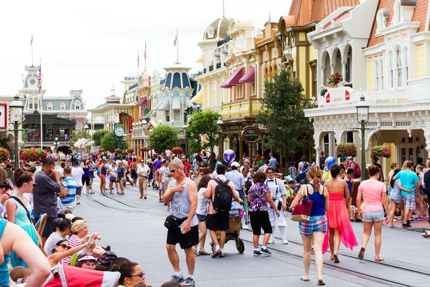 Orlando, USA - August 4, 2013: View of the people and families that cross Main Street USA, the entrance to Magic Kingdom amusement park at Walt Disney World with restaurants and souvenir stores. Shoot at mid day during the high summer season.
