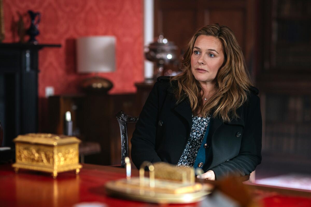 A woman wearing a dark jackets sits in a chair.