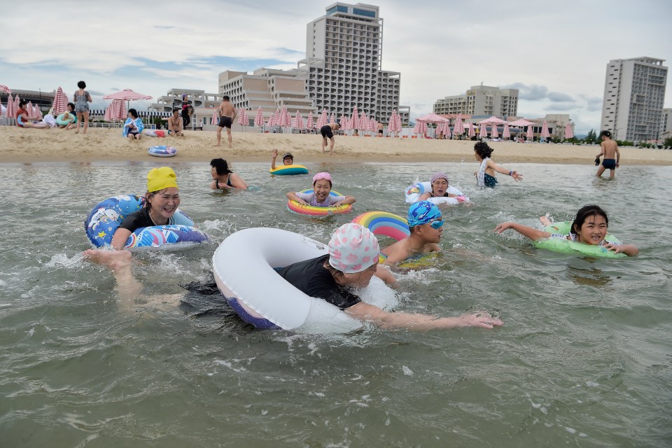 People enjoying a beach day, swimming in the ocean with inflatable rings.