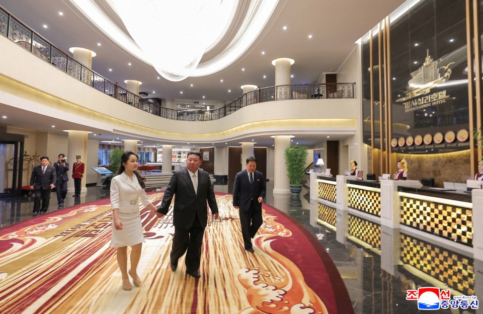 Kim Jong Un and his wife walking through a hotel lobby.