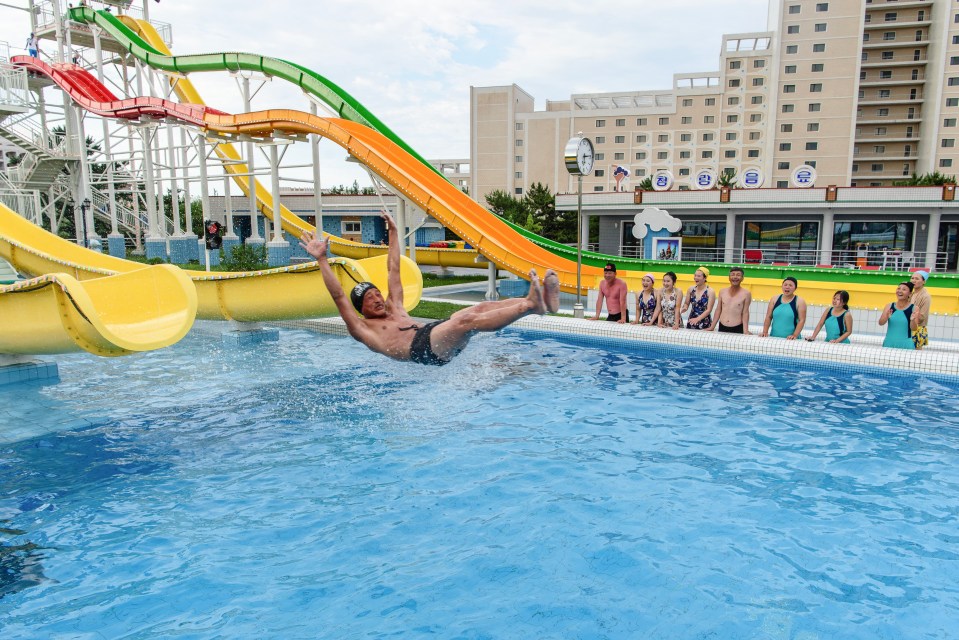 Man falling into a swimming pool from a water slide.