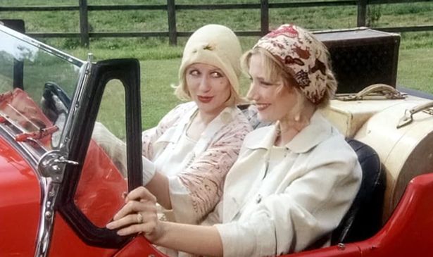 Two women drive in a red car 