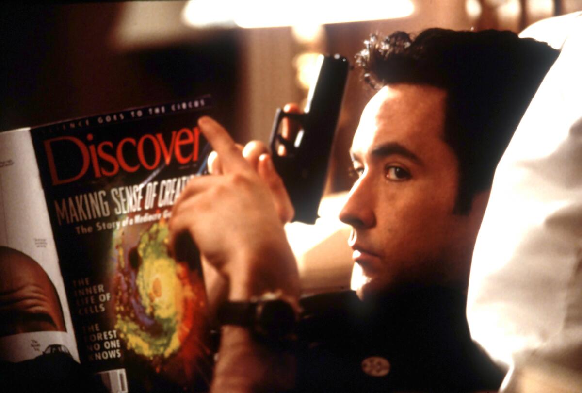A man with a gun reads a magazine.