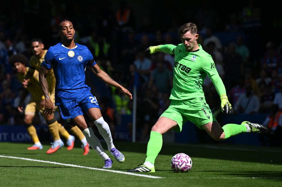 Photo of a soccer goalie diving to clear the ball as a forward approaches.