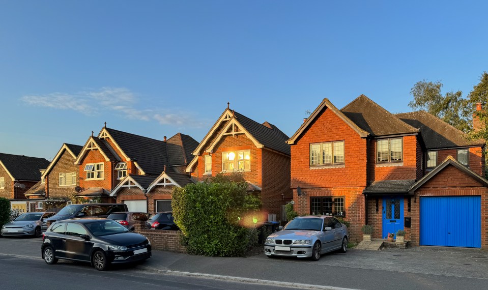 Houses and cars on a suburban street at sunset.