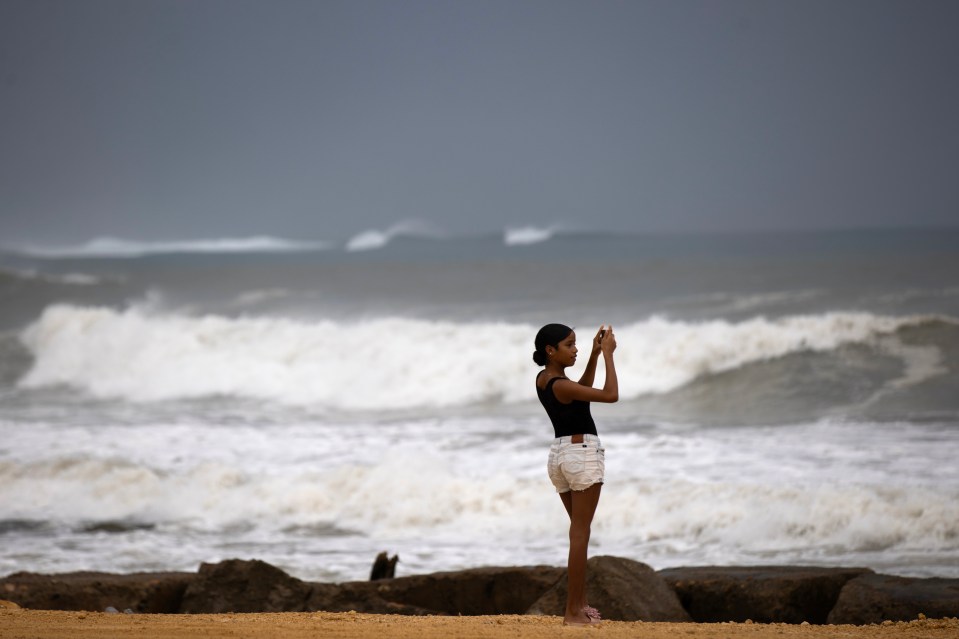 Person photographing rough seas during a hurricane.