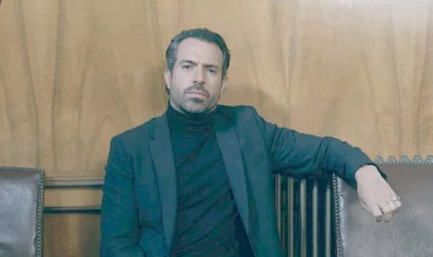 A man in a suit sits on a chair