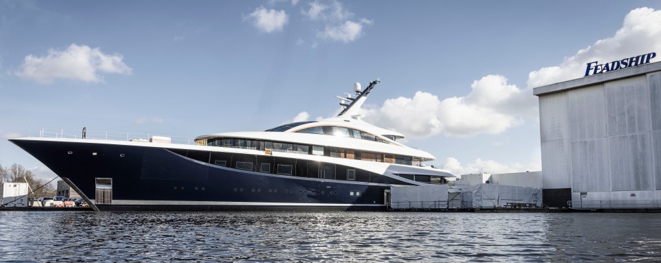 Large yacht in the water near a Feadship building.