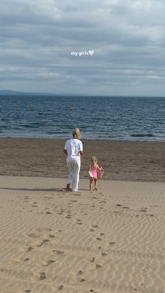 Woman and toddler walking on a beach.