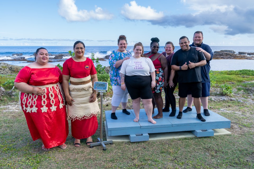 Group of people standing on a scale by the ocean.