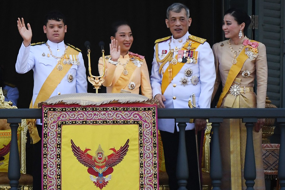 Thai King Maha Vajiralongkorn, Queen Suthida, Princess Bajrakitiyabha Mahidol, and Prince Dipangkorn Rasmijoti on a balcony.