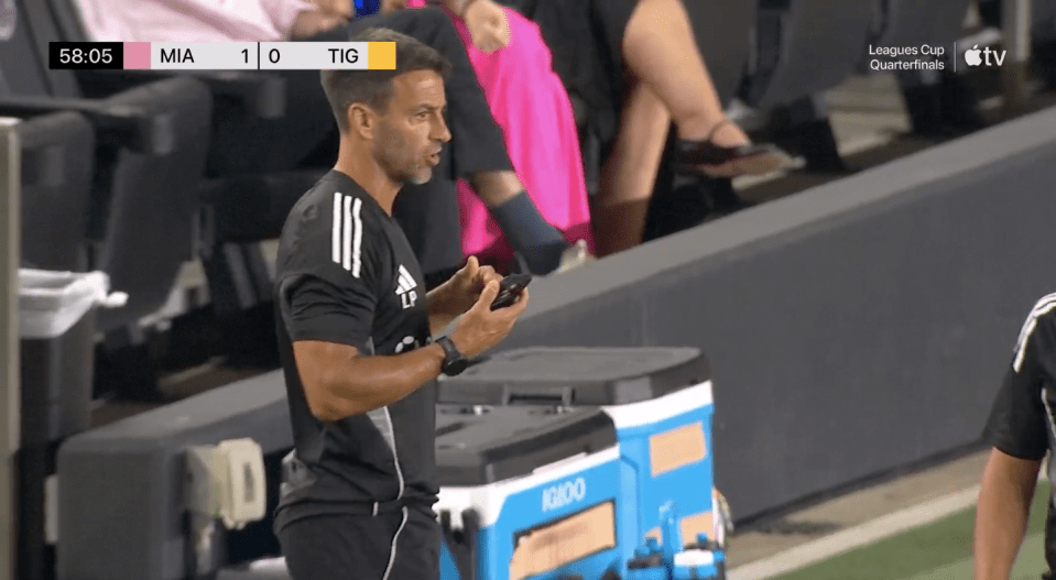 Screenshot of a soccer coach looking at his phone during a Leagues Cup quarterfinal.