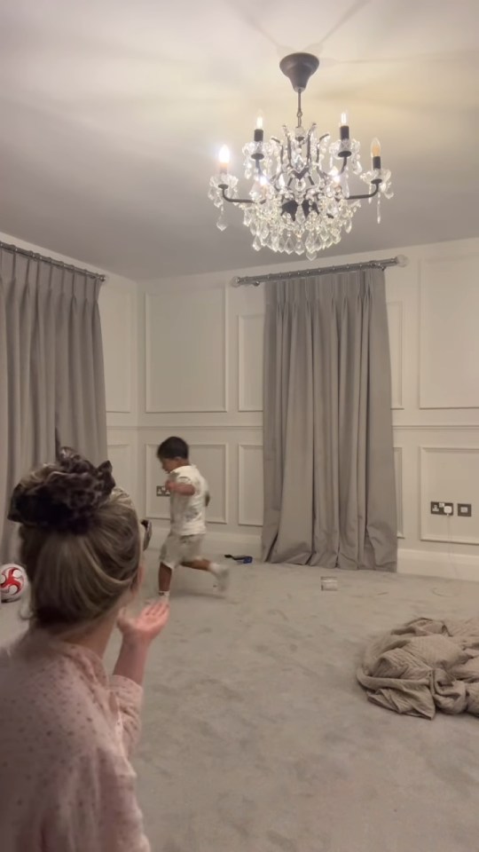 Woman trying to calm a young child running around a room.