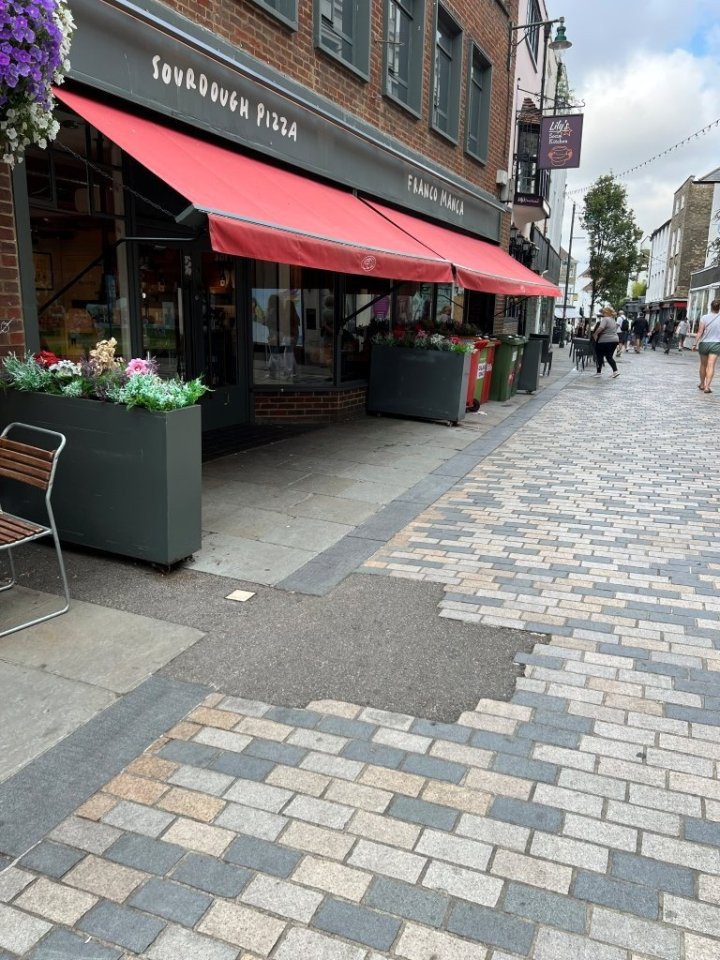 Tarmac repair on a cobbled street in front of a restaurant.