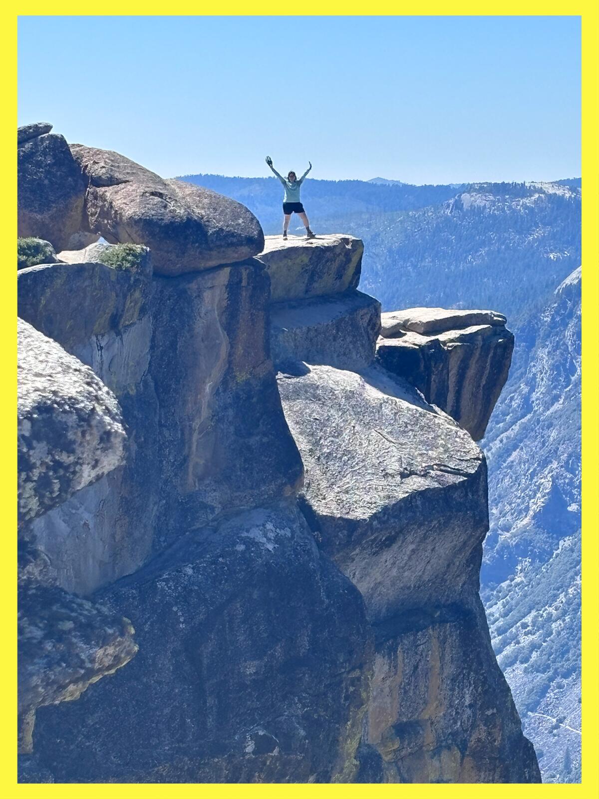 A person in the distance celebrates their successful jaunt to Taft Point, an epic lookout point in Yosemite National Park.